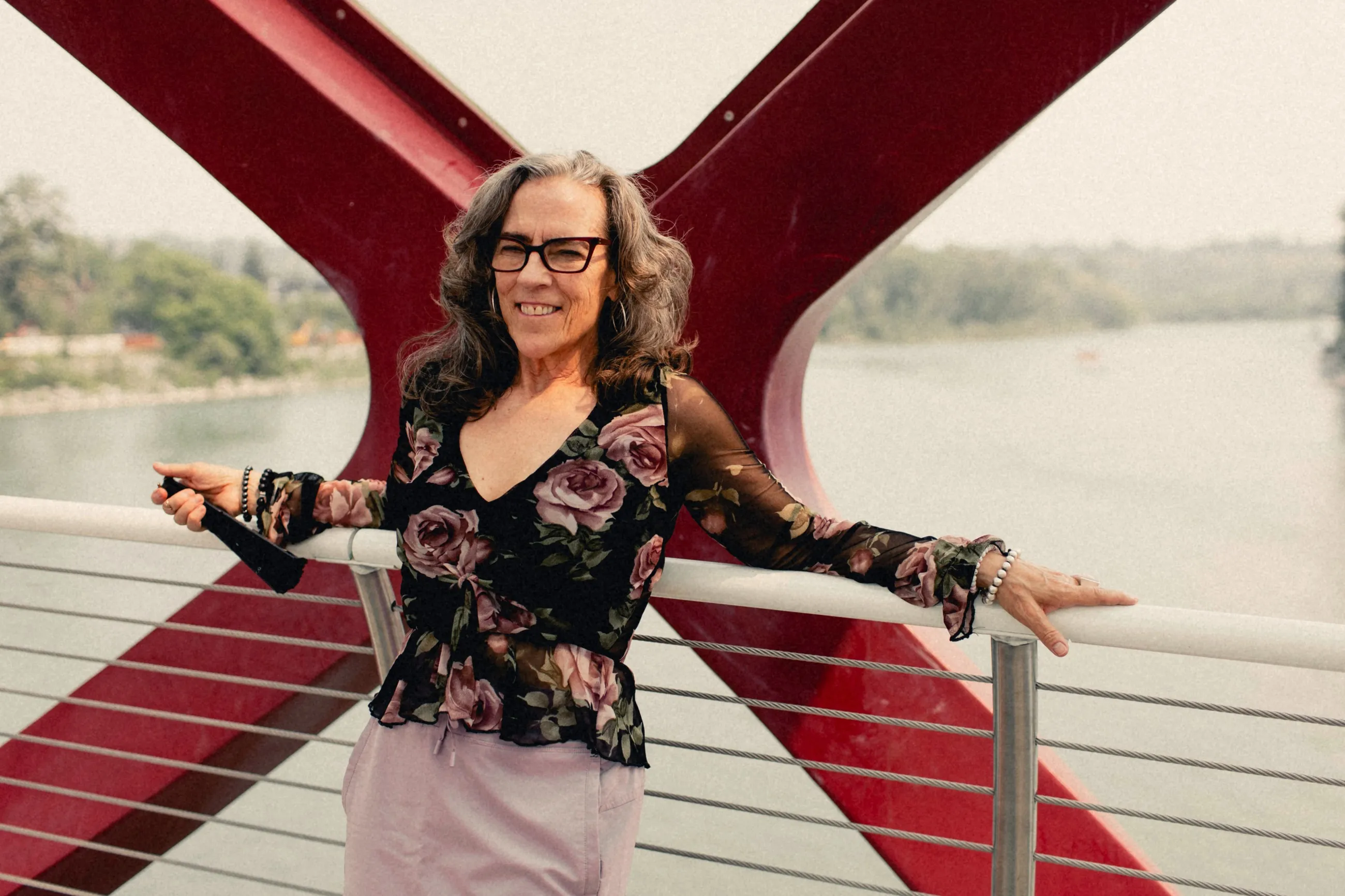 Heidi Barkwell laughing with her arms spread wide on the Peace Bridge