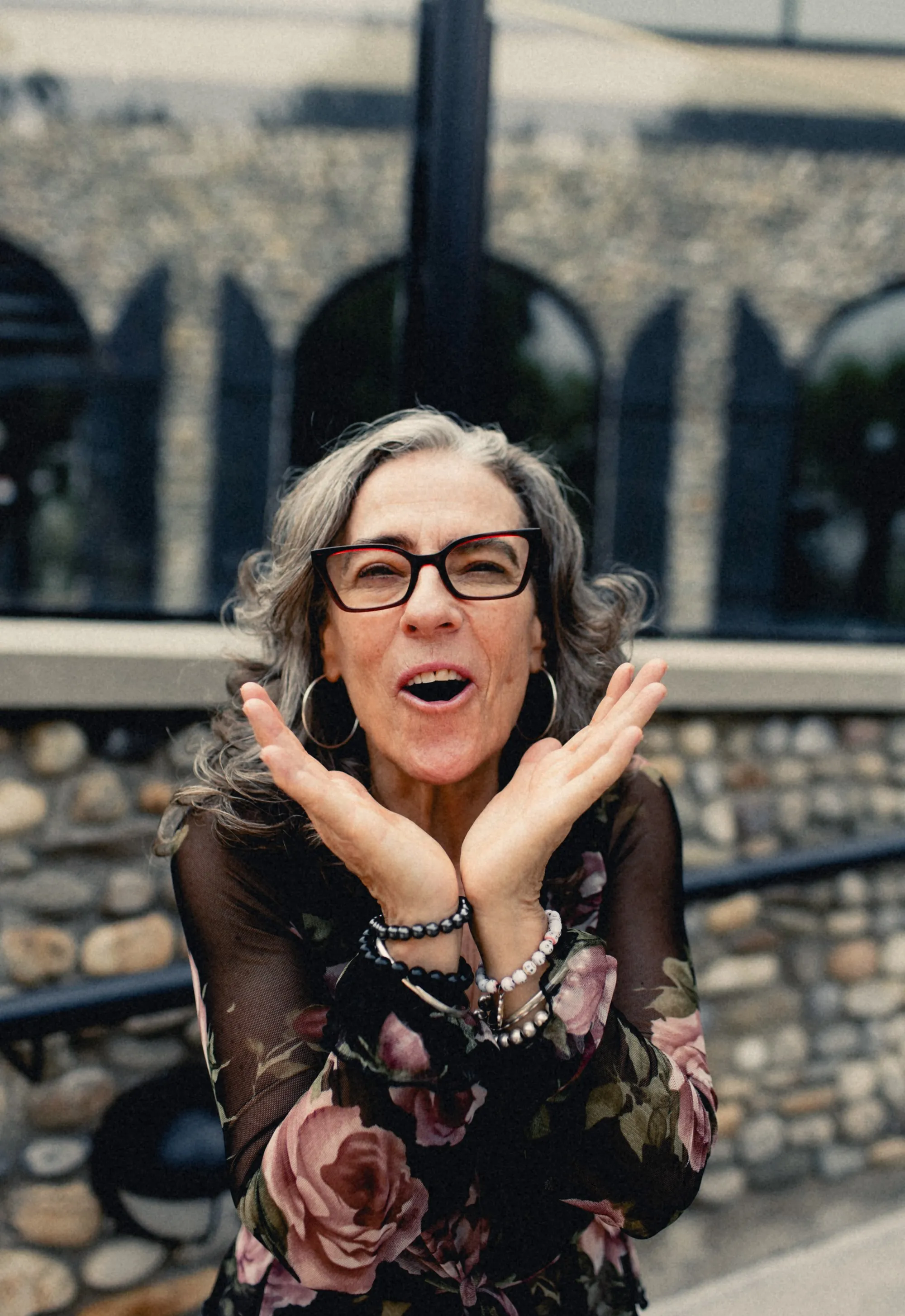 Heidi with hands under her chin in front of stone arches