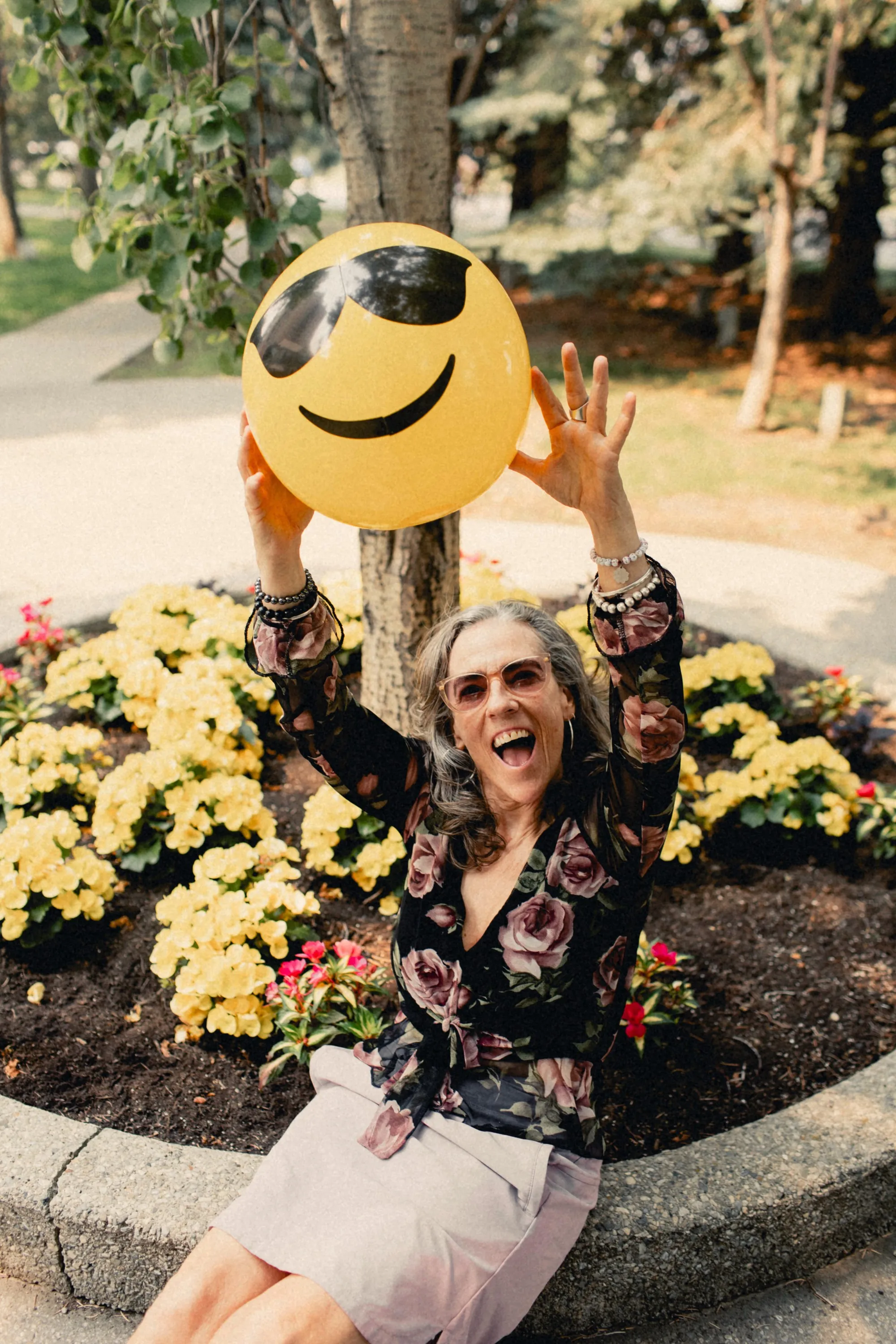 Heidi tossing a smiley-face ball in a flower bed