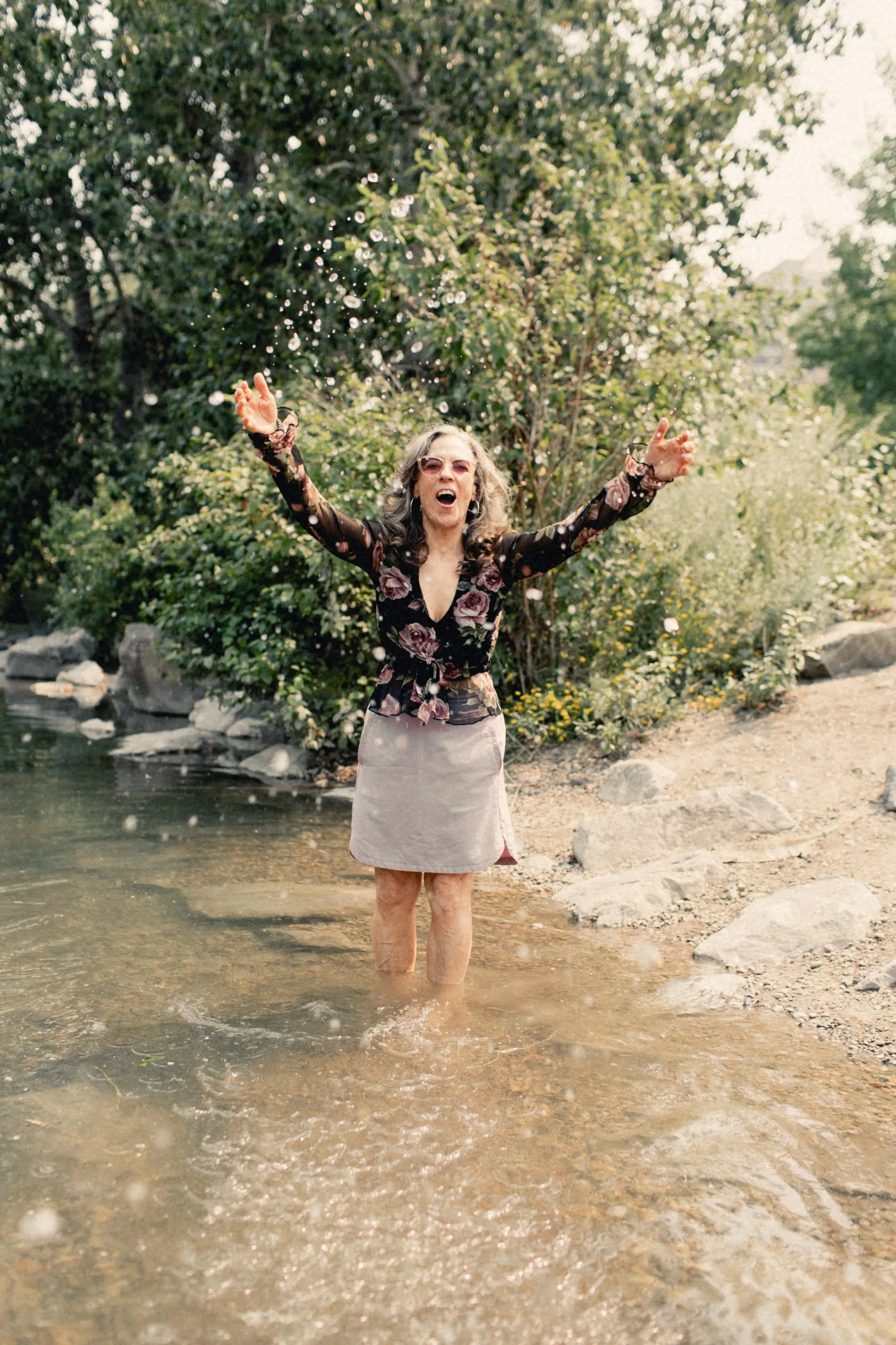 Heidi standing in the Bow River with her arms raised