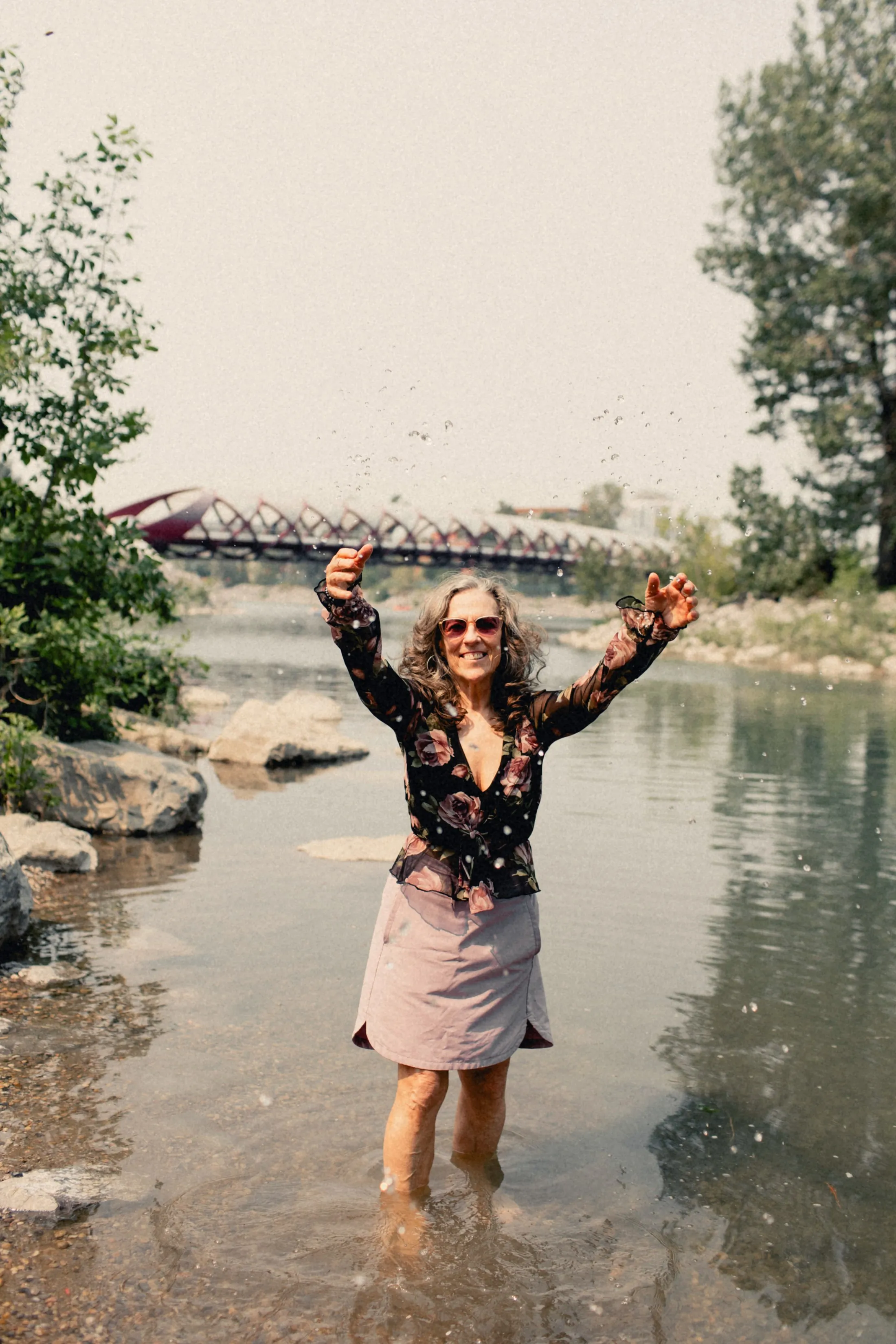 Heidi standing in the Bow River with her arms in the air