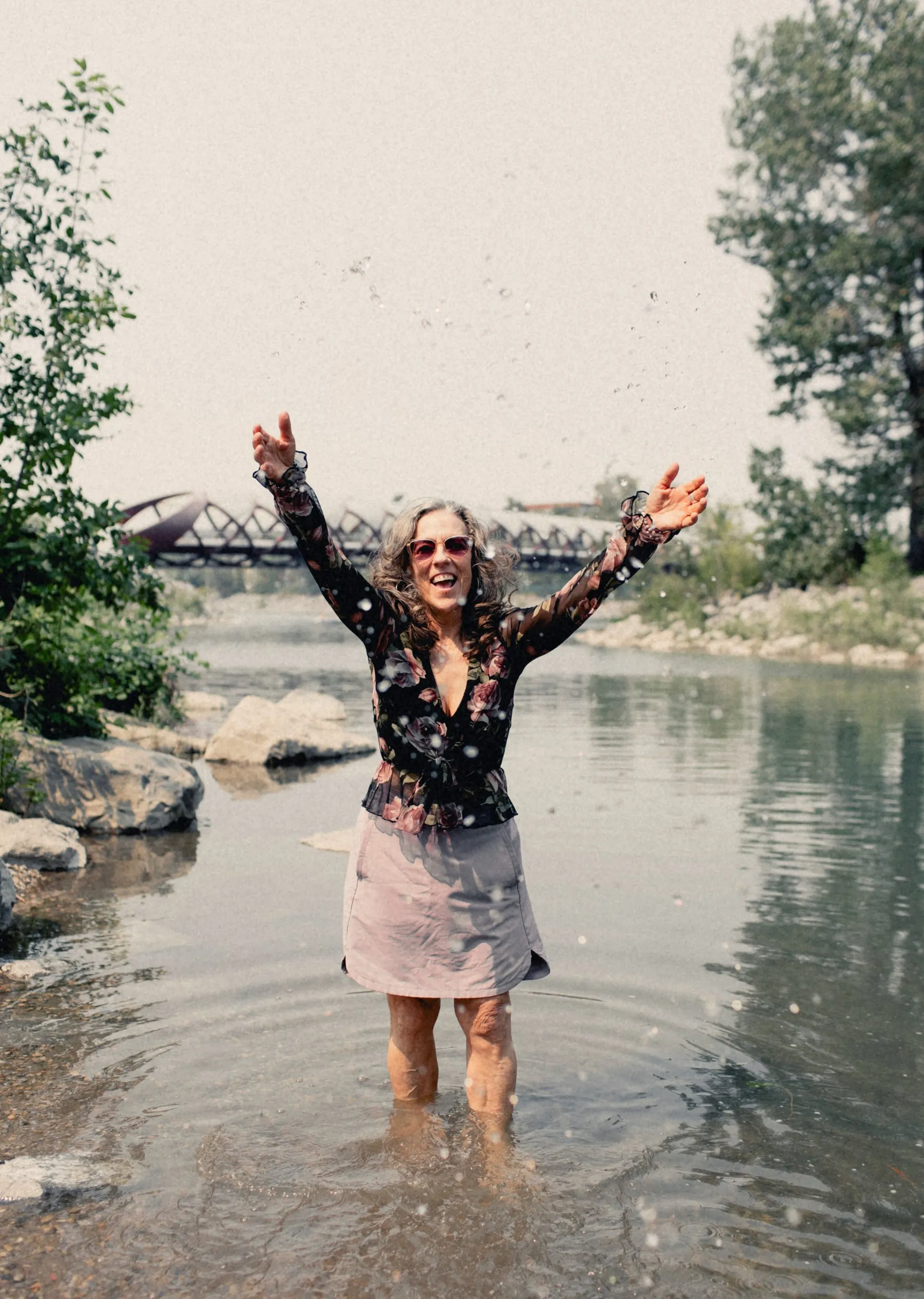 Heidi celebrating with her arms up, standing in the Bow River
