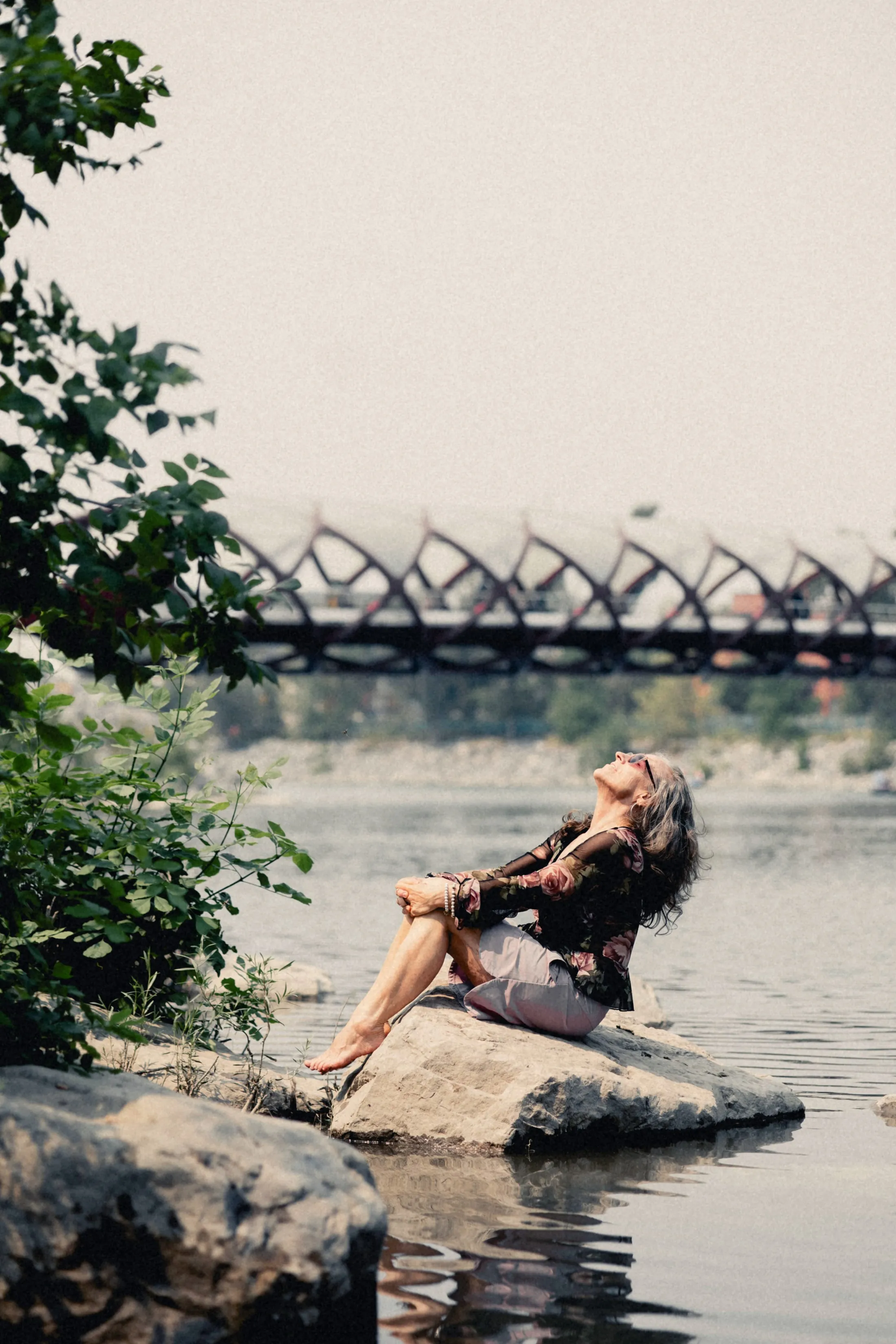 Heidi sitting on a rock with the Peace Bridge behind