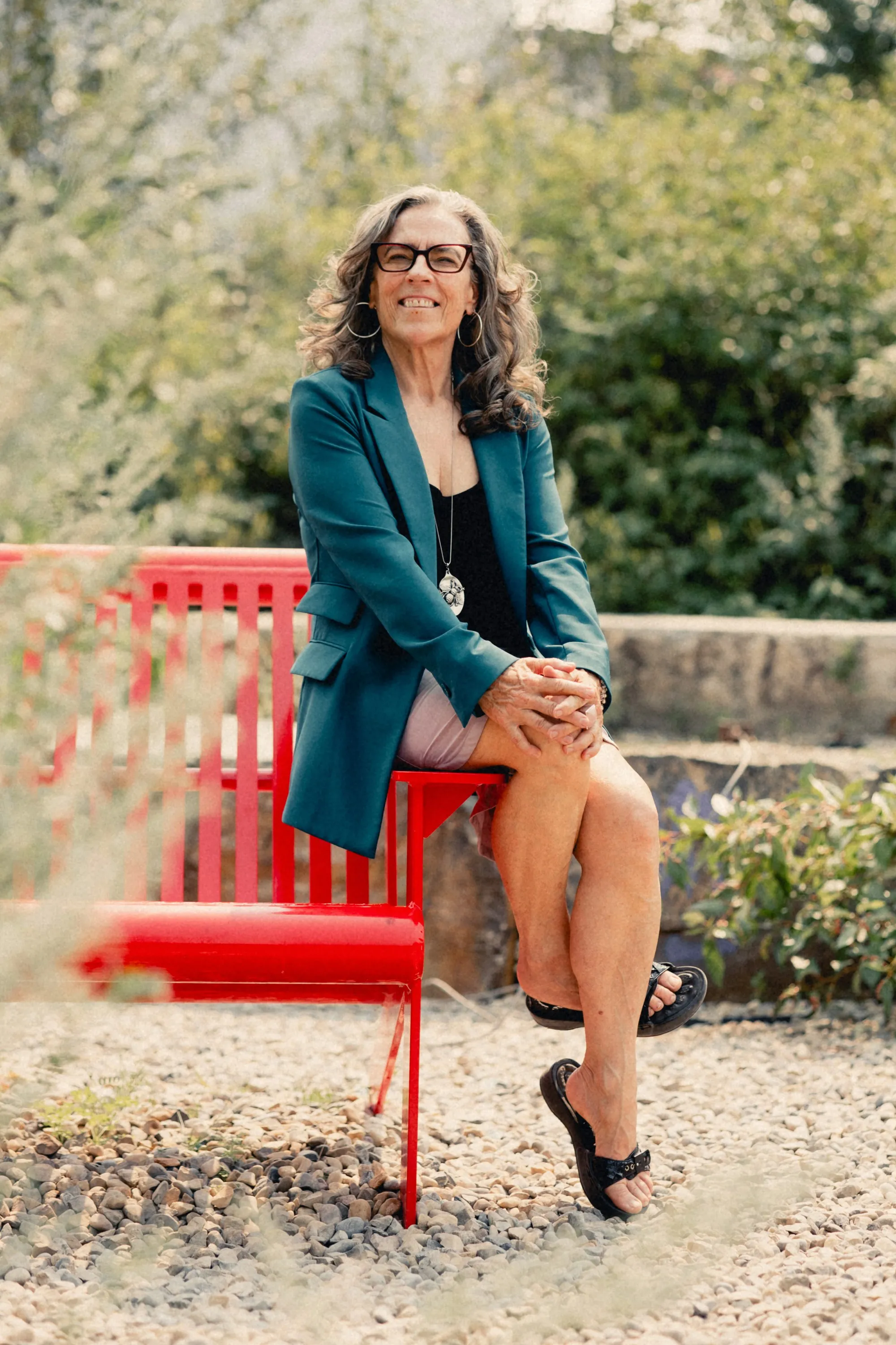 Heidi seated on a red bench, hands folded