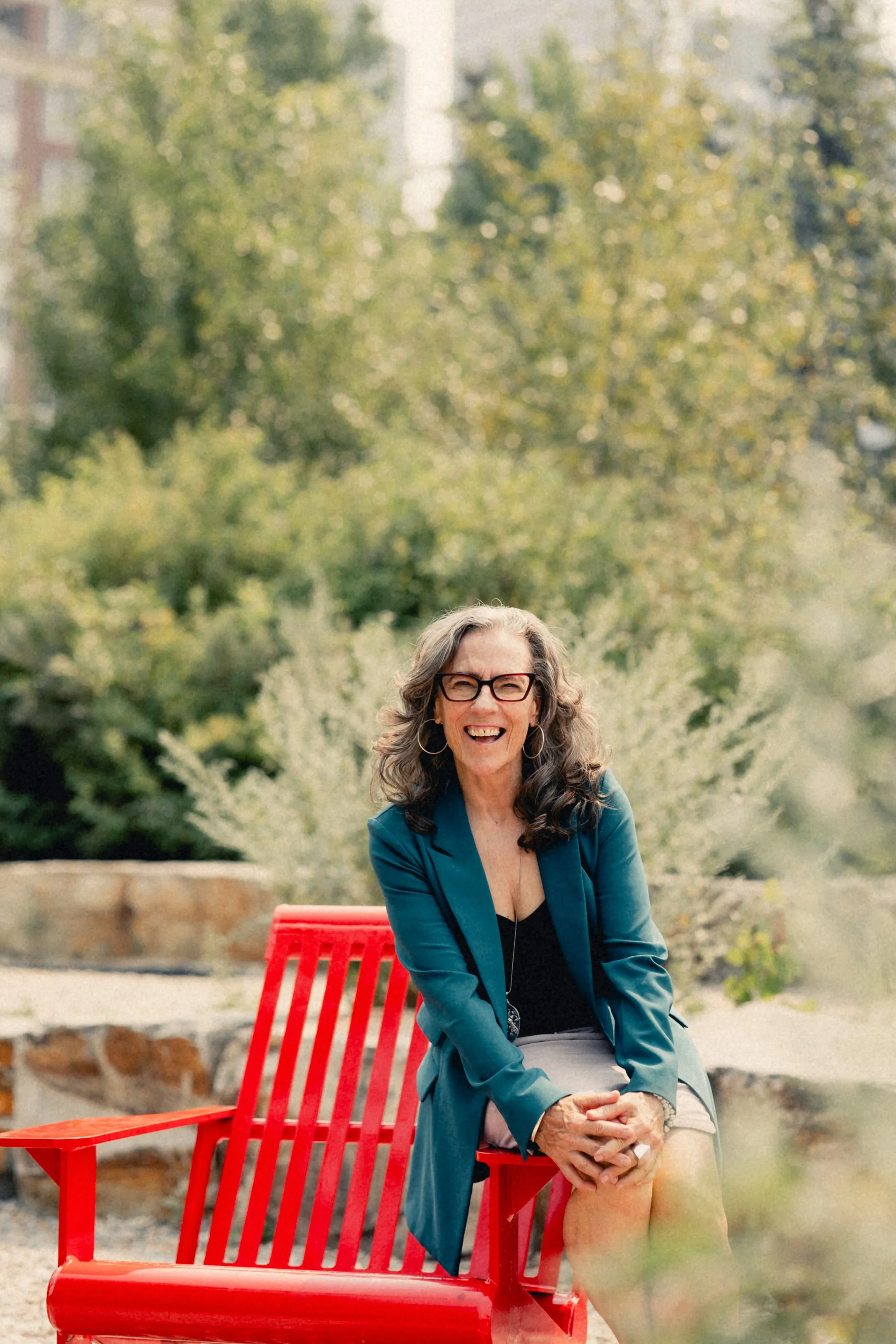 Heidi standing beside a red chair, laughing
