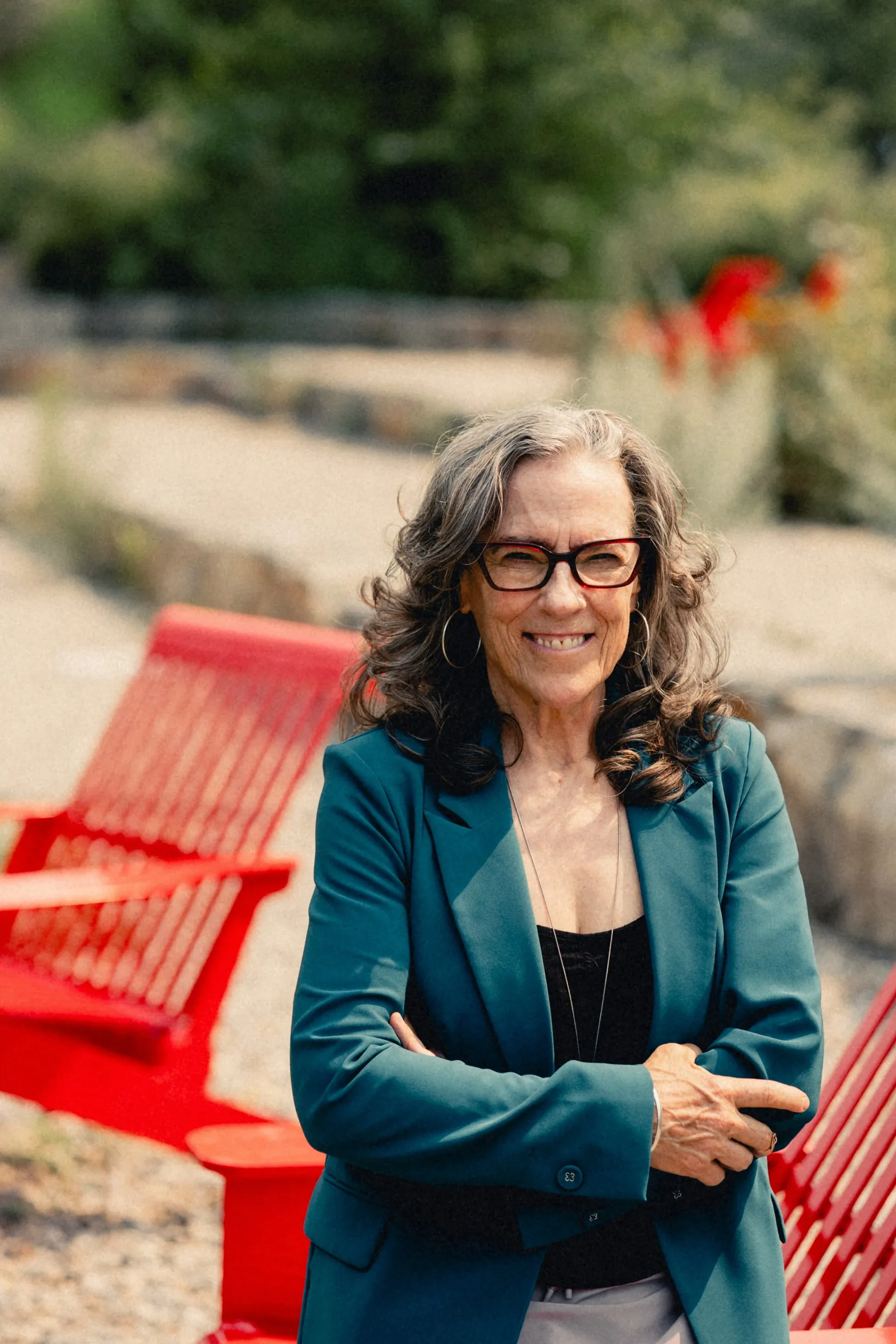 Heidi with arms crossed, smiling on a red bench